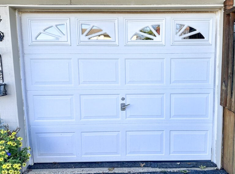 White raised-panel garage door with sunburst windows on a home's exterior