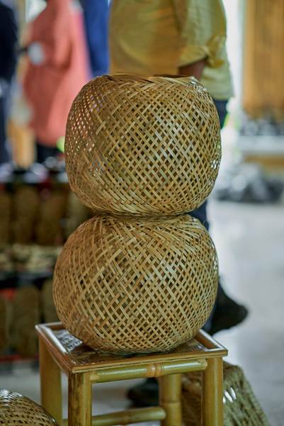 Two round woven bamboo baskets stacked on a small bamboo stool