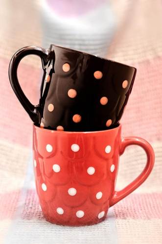 Black mug with orange polka dots stacked inside a red polka-dot mug