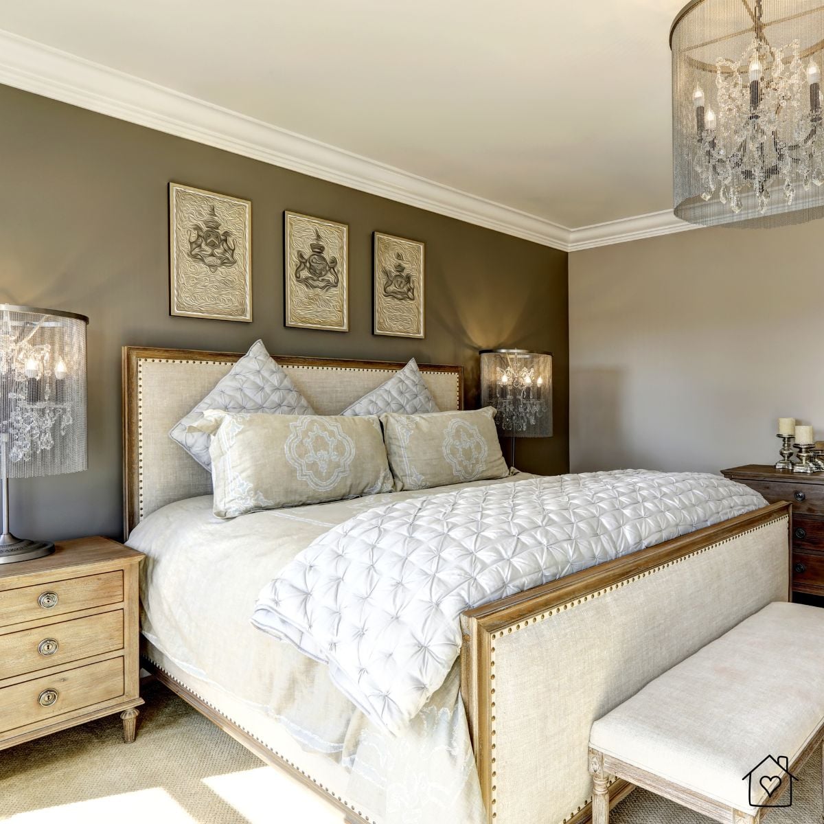 Luxurious bedroom with an upholstered linen bed, quilted bedding, crystal chandelier, and wood nightstands