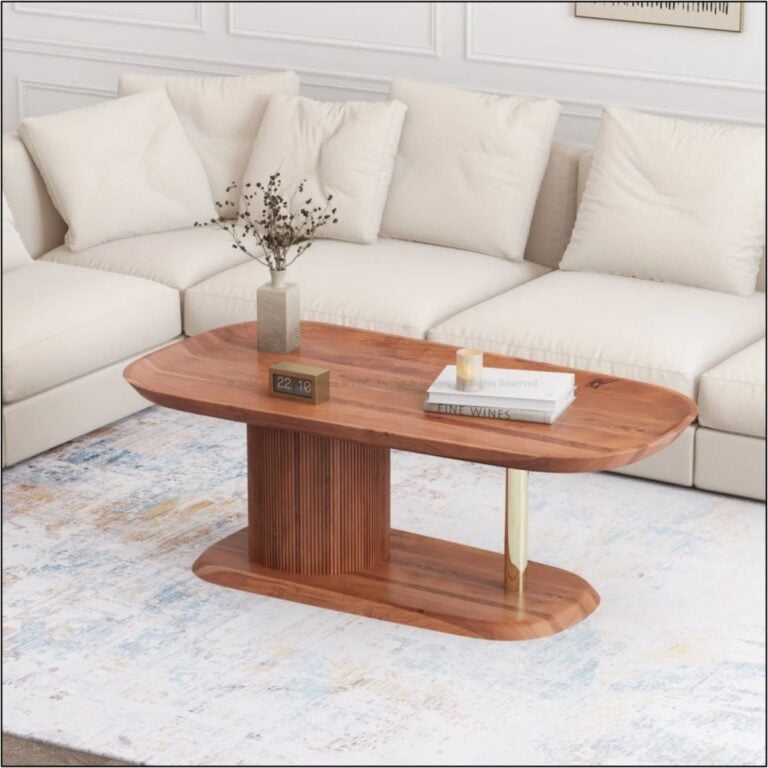 Oval wooden coffee table with a fluted pedestal base and brass leg in front of a cream sectional sofa